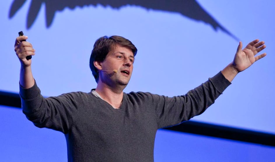 Maciej Cegłowski speaking at a conference-arms spread wide with a clocker in his left hand.