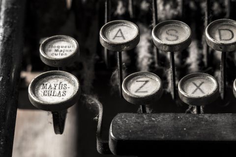 Close-up of vintage typewriter keys with visible dust and grime, including Spanish-language keys such as "MAYÚS-CULAS" and "bloqueo de mayúsculas".