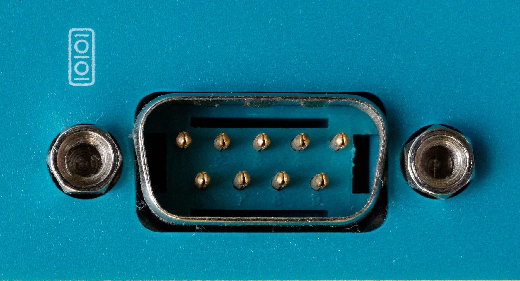 Close-up of a 9-pin male D-sub connector port with two hexagonal screw holes on a blue device