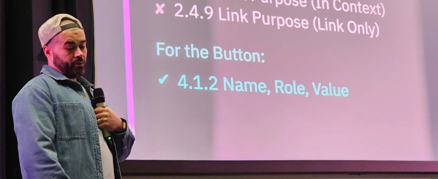 Person wearing a backwards cap and denim jacket speaking into a microphone in front of a projected presentation slide discussing web accessibility guidelines, highlighting WCAG success criterion 4.1.2 'Name, Role, Value' for buttons.