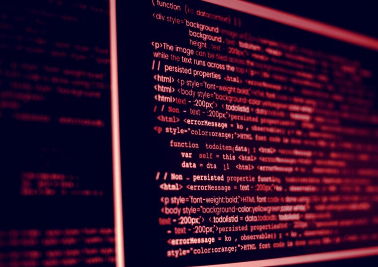 Red-tinged computer screen displaying HTML and JavaScript code with multiple lines and syntax highlighting.